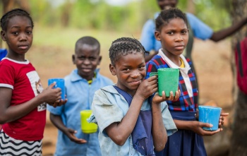 A girl happily holding her cup of porridge