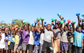 Children happily holding their porridge cups before getting served