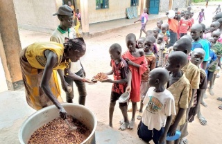 Essen wird an in einer Schlange wartende Kinder in einer Schule im Südsudan serviert.