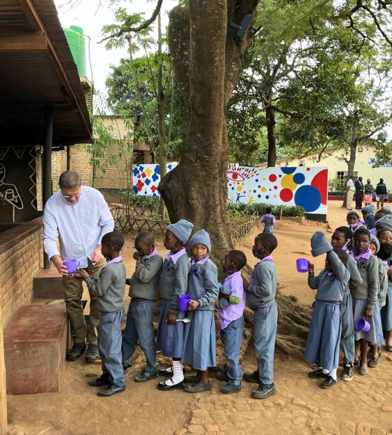 Magnus MacFarlane-Barrow serviert Kindern in Malawi Essen.