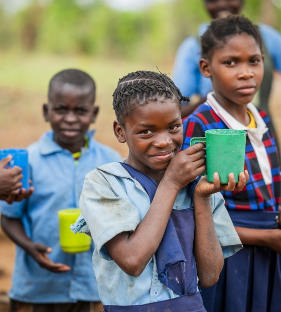 A girl happily holding her cup of porridge